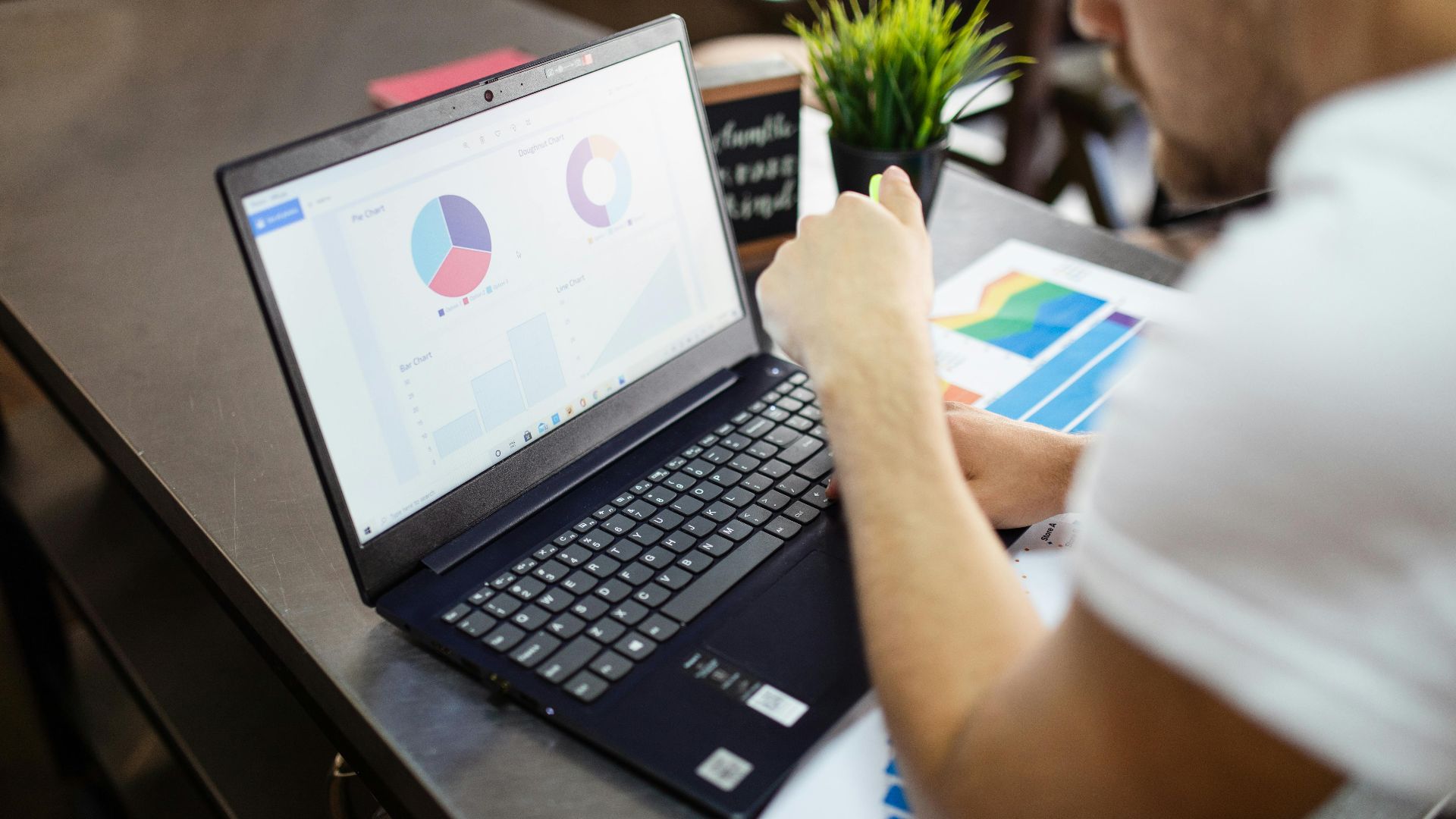 Man reviewing charts and graphs on a laptop for business analysis.