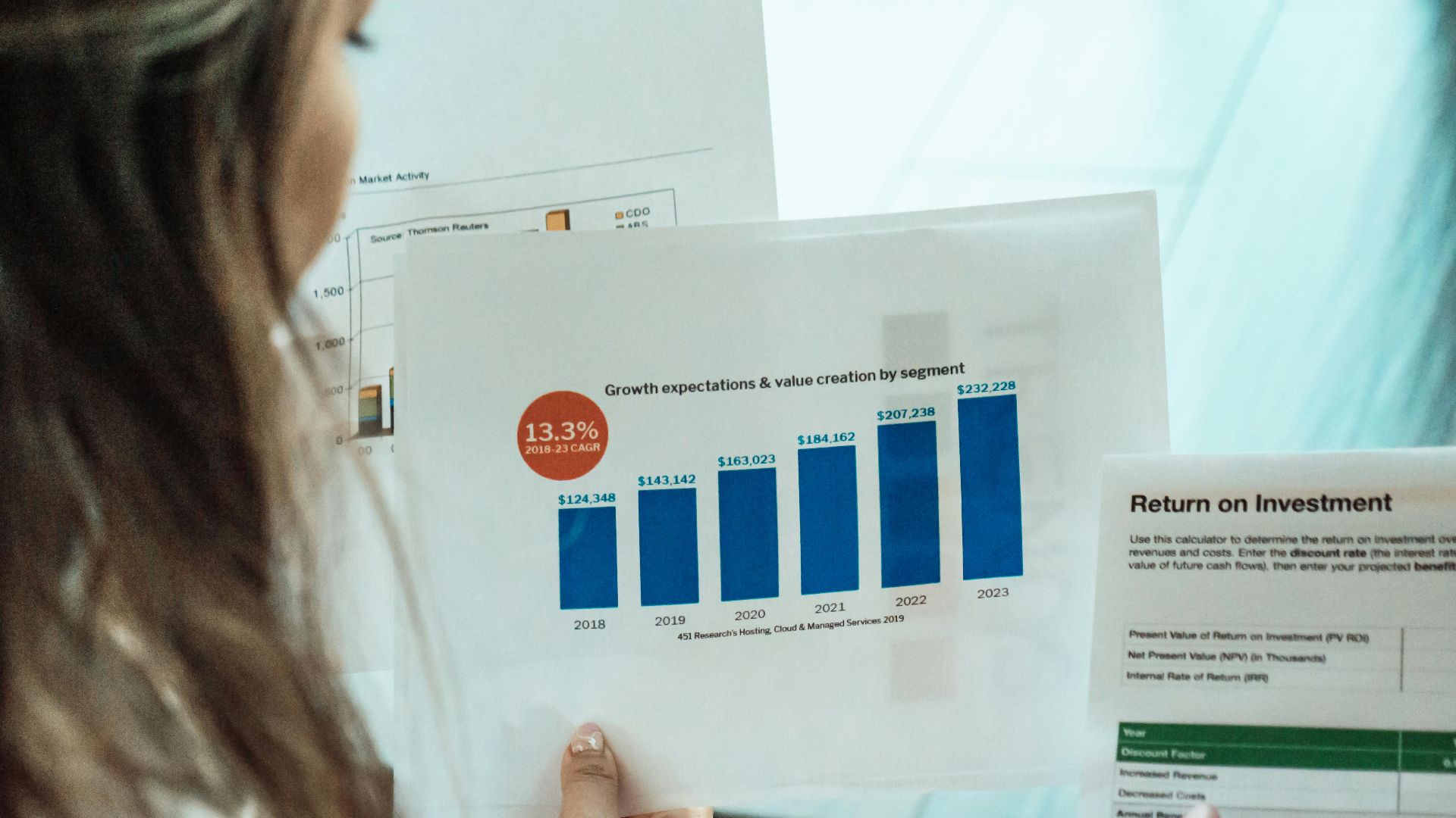 Person analyzing financial graphs and ROI reports, focusing on investment growth.