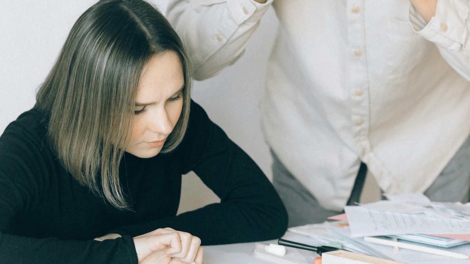 Young couple in discussion over financial papers, looking stressed at a table indoors.