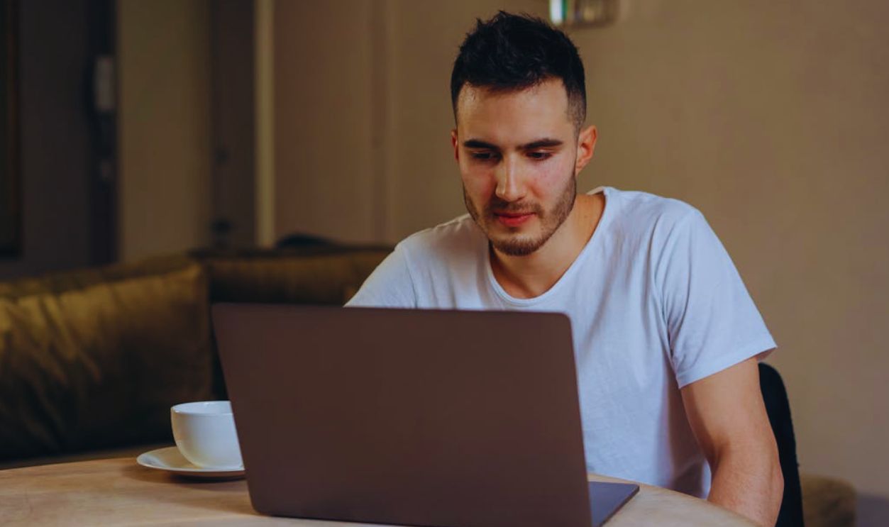 Man in White Shirt using Gray Laptop