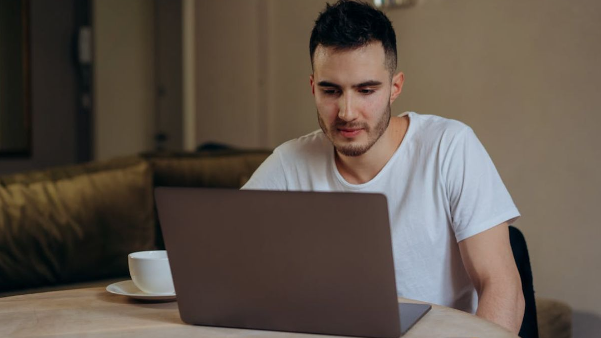 Man in White Shirt using Gray Laptop