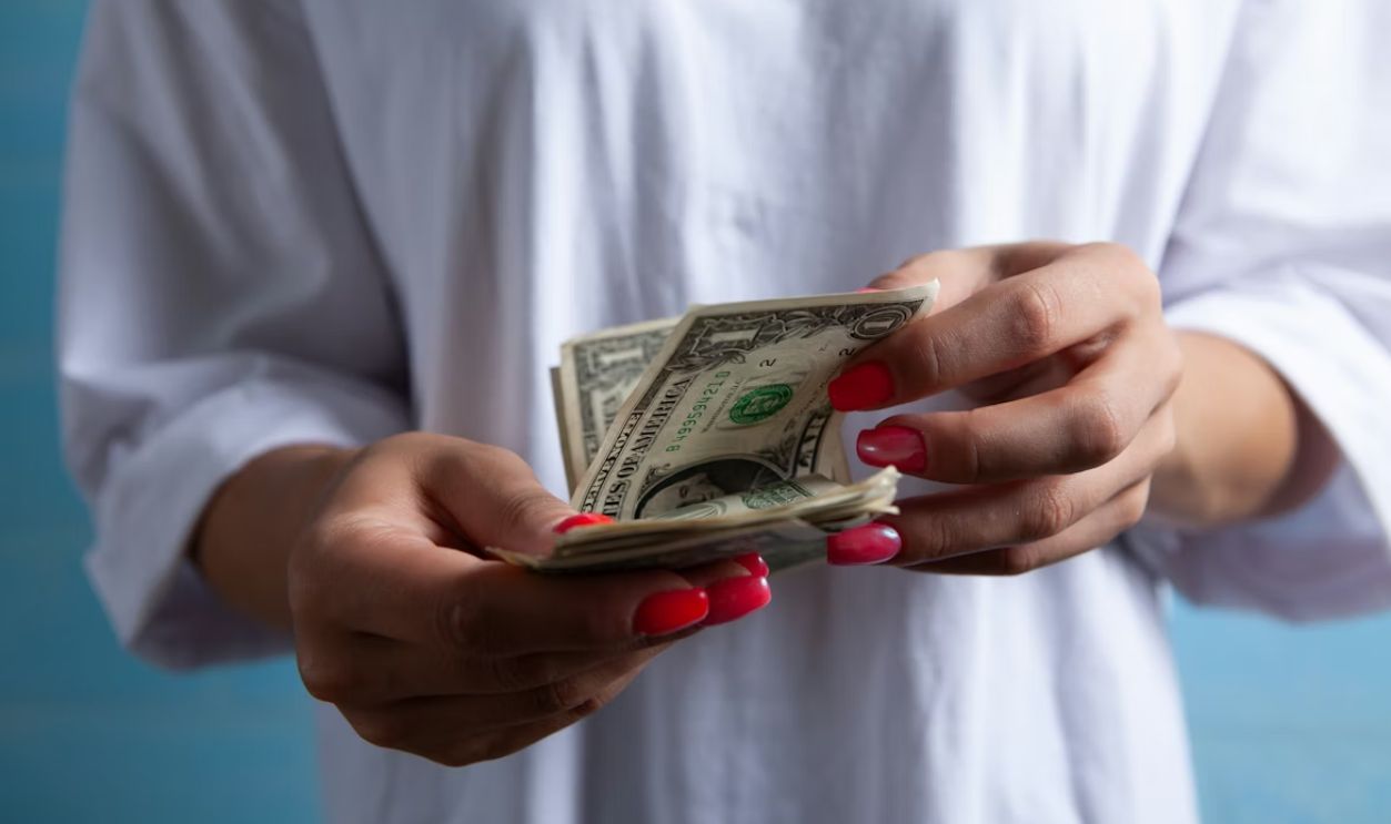 Hands holding a stack of dollar bills