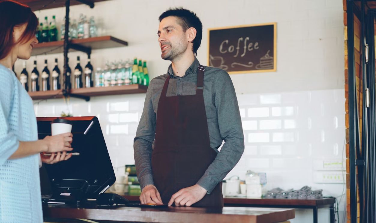 A barista is serving a customer coffee