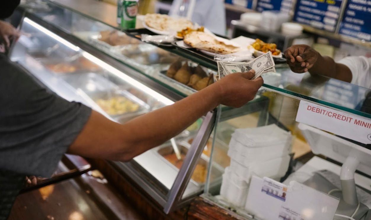 Person paying money for food in cafe