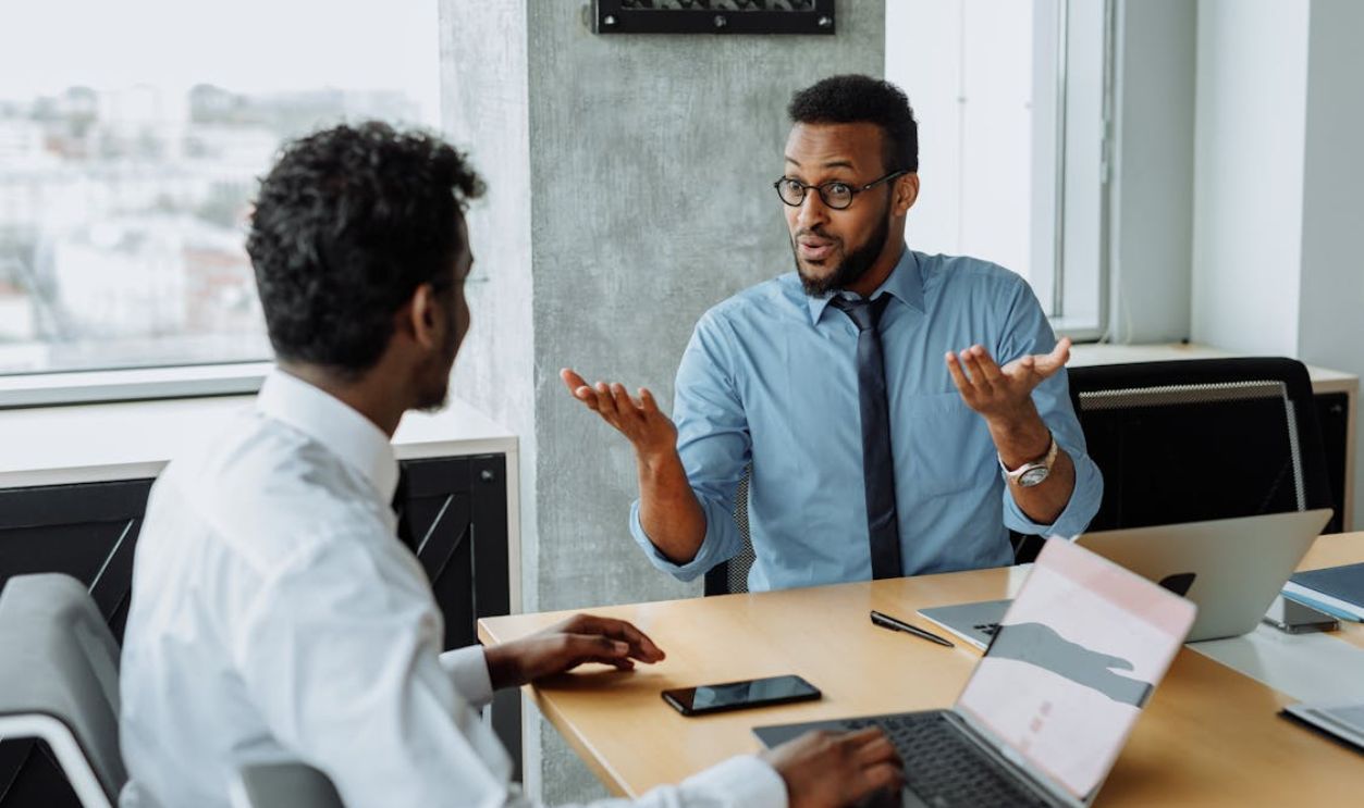 Man in Blue Long Sleeve Shirt Talking to a Man in White Long Sleeve Shirt