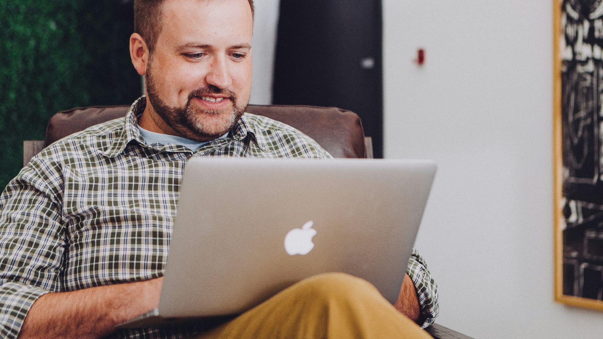 man smiling and using MacBook