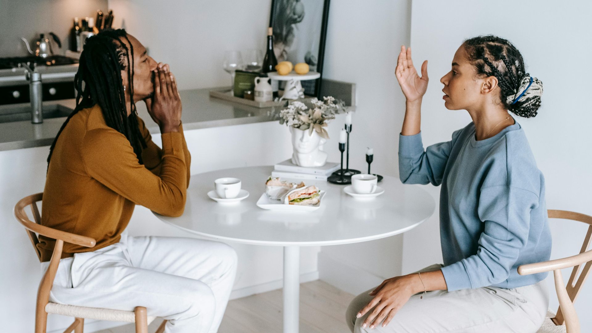 A couple in an intense conversation at a kitchen table, highlighting relationship dynamics.