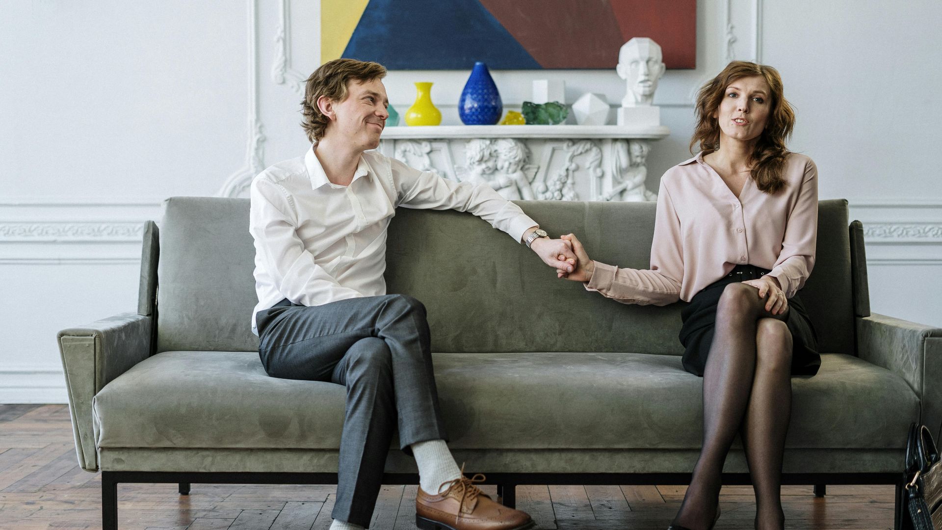 A couple in a therapy session holding hands, conveying support and connection.