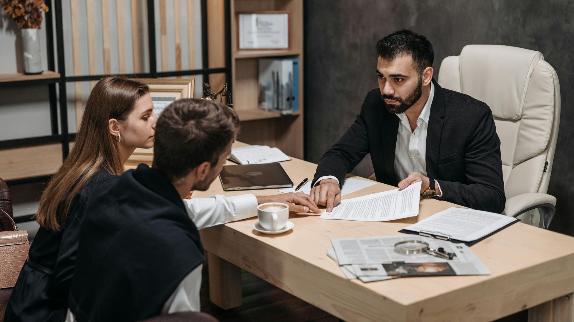 Lawyer discussing legal documents with clients at office desk.