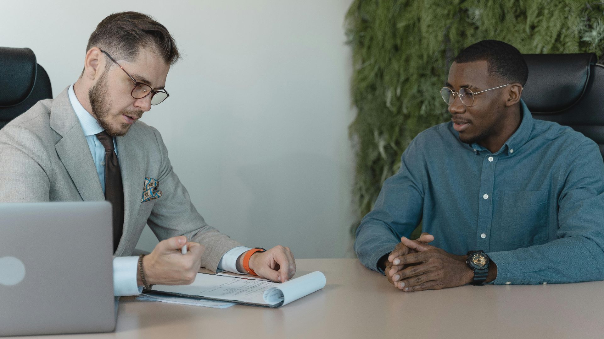 A professional job interview between two men in a modern office environment.