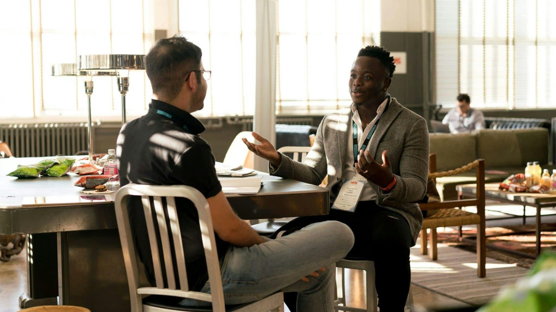 Two men having a casual discussion in a bright indoor setting, highlighting mentorship.