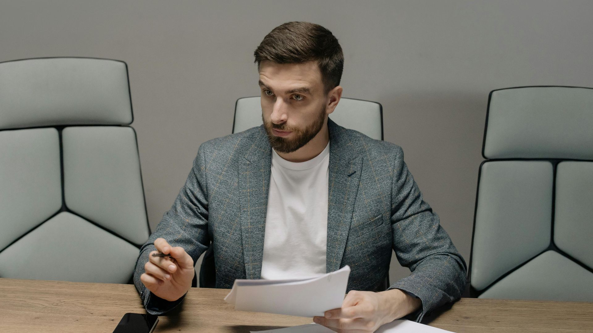 Professional businessman in a suit holding documents during a meeting in an office setting.