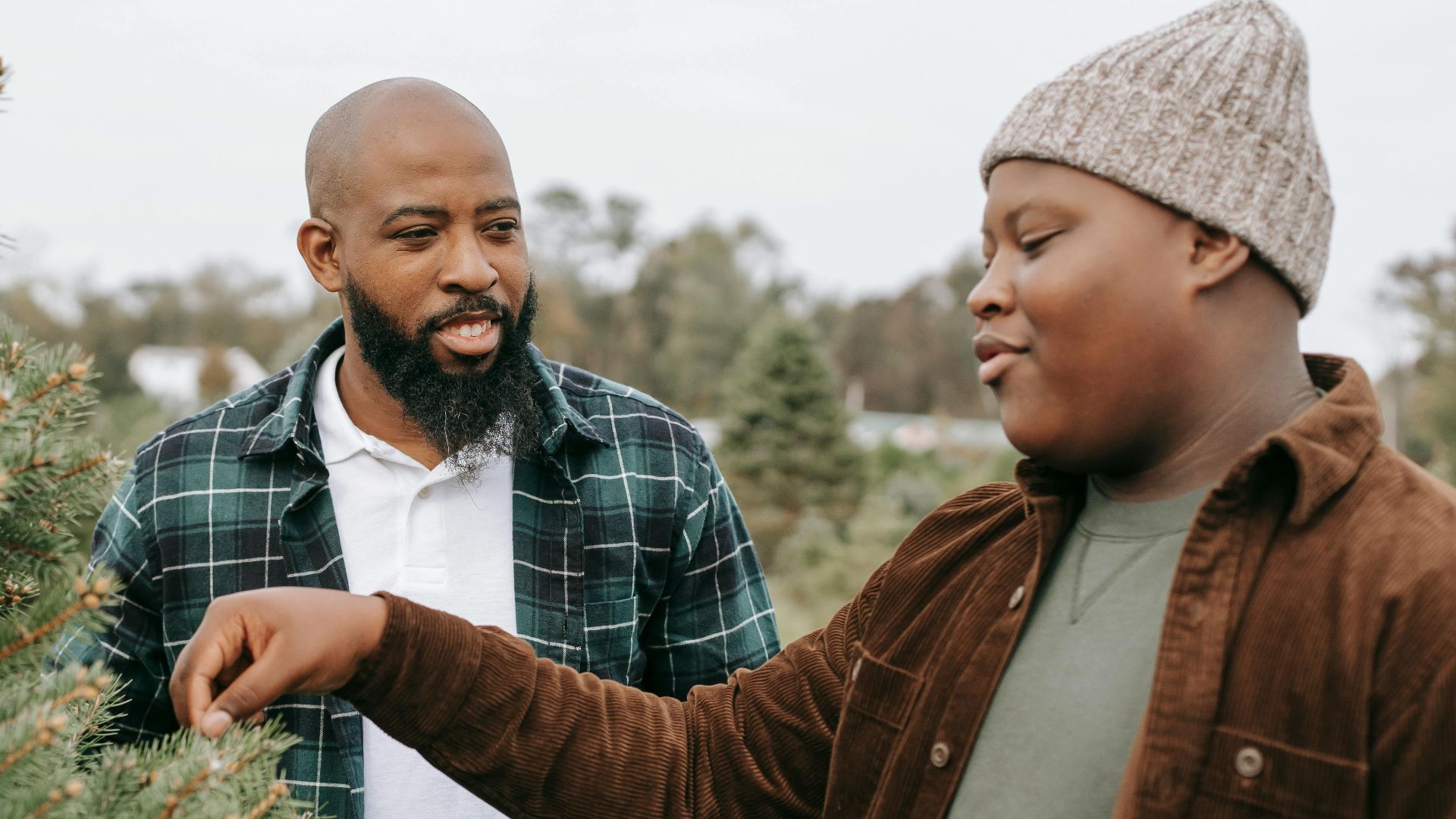 Father and son picking a Christmas tree together at a tree farm, enjoying a holiday outing.