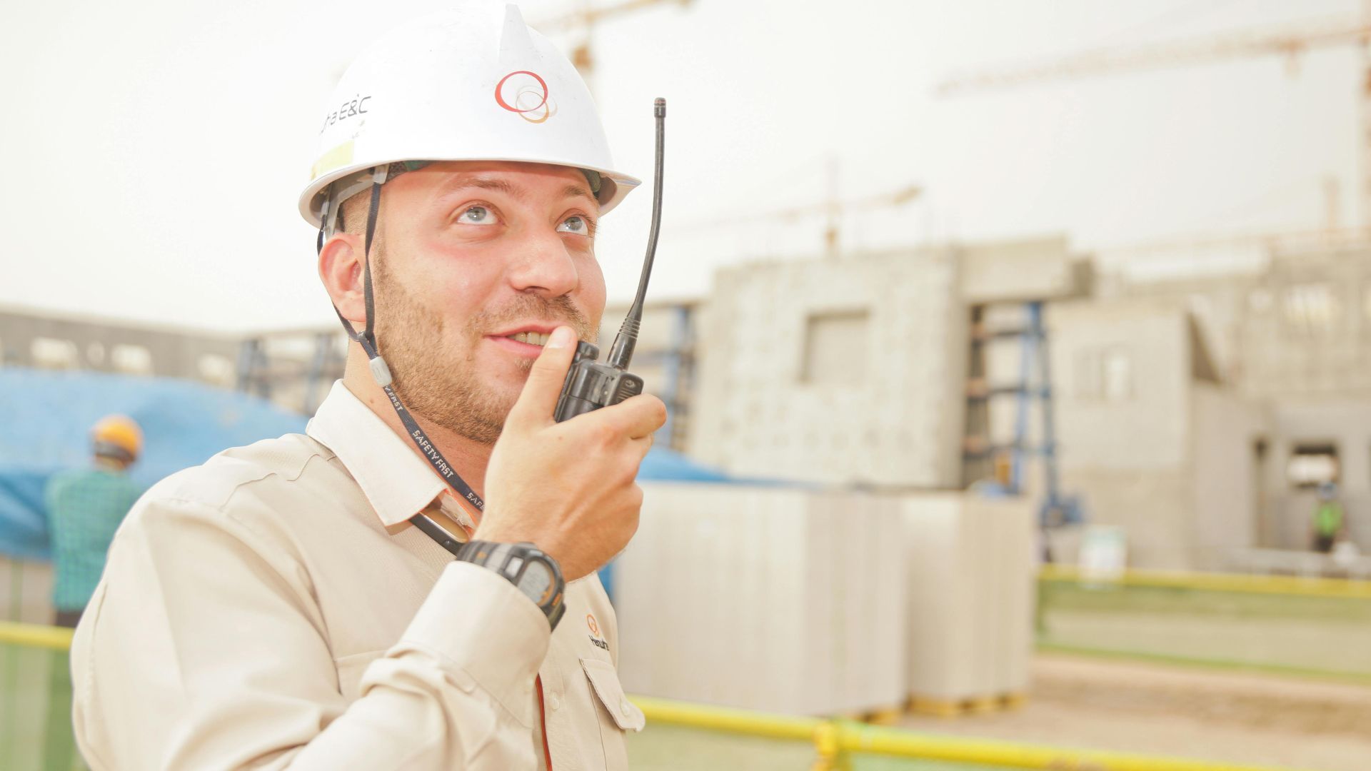 Male construction worker using radio on a building site, wearing a safety helmet, communicating effectively.