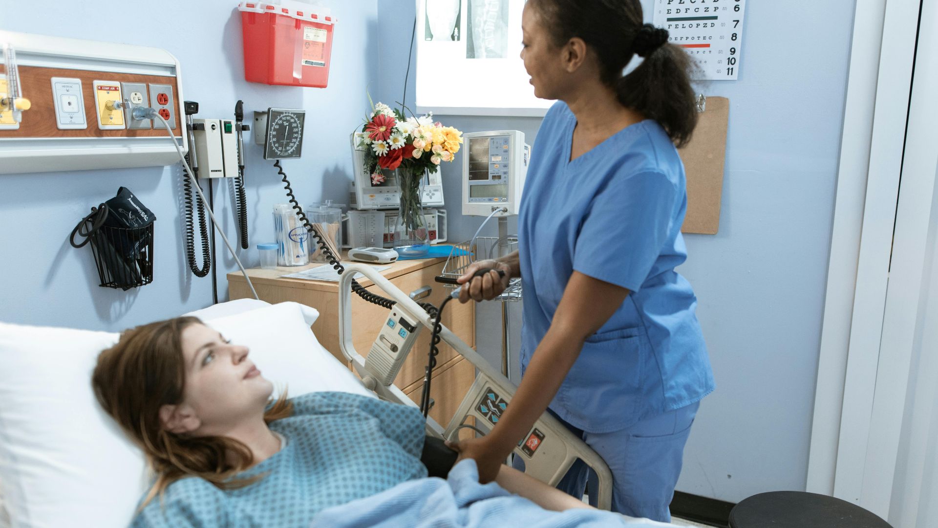 Nurse providing care to a patient in a hospital room with medical equipment.
