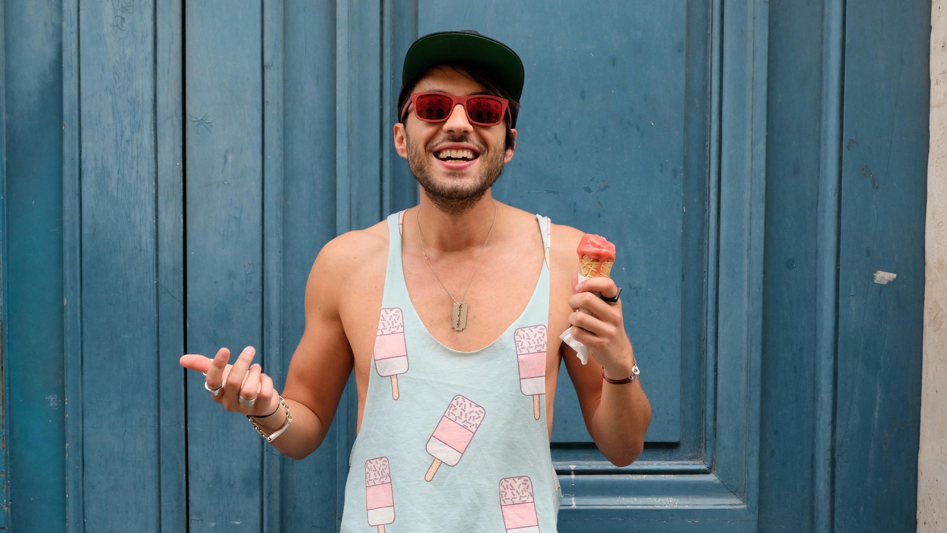 Happy man in Paris enjoying ice cream against a blue door. Fashionable and fun summer vibe.