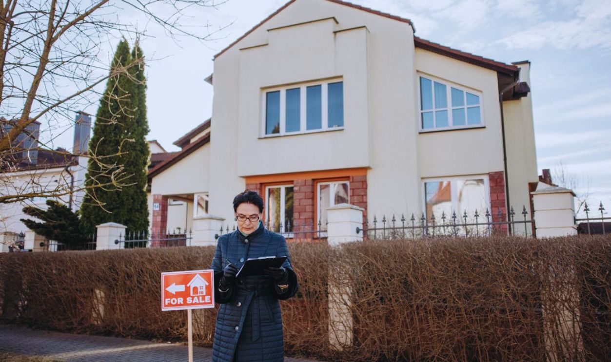 Woman in Jacket Standing by House for Sale