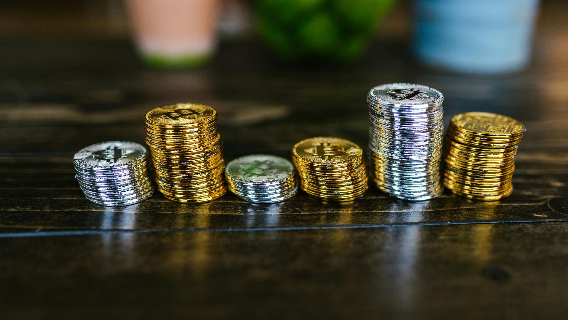 Pile of shiny gold and silver cryptocurrency coins on a wooden table.