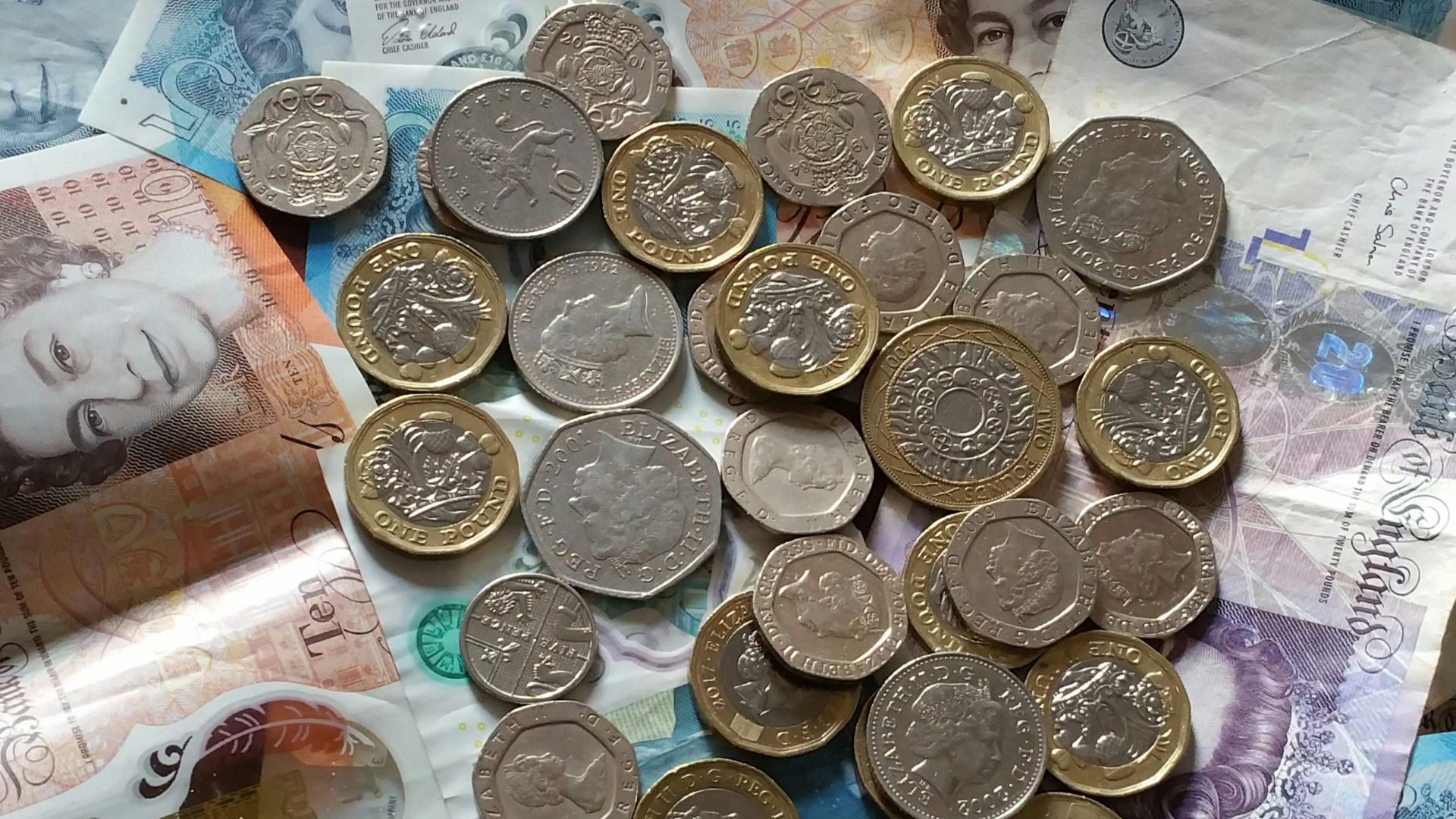 A detailed image of British Pound Sterling coins and banknotes, perfect for finance-related projects.