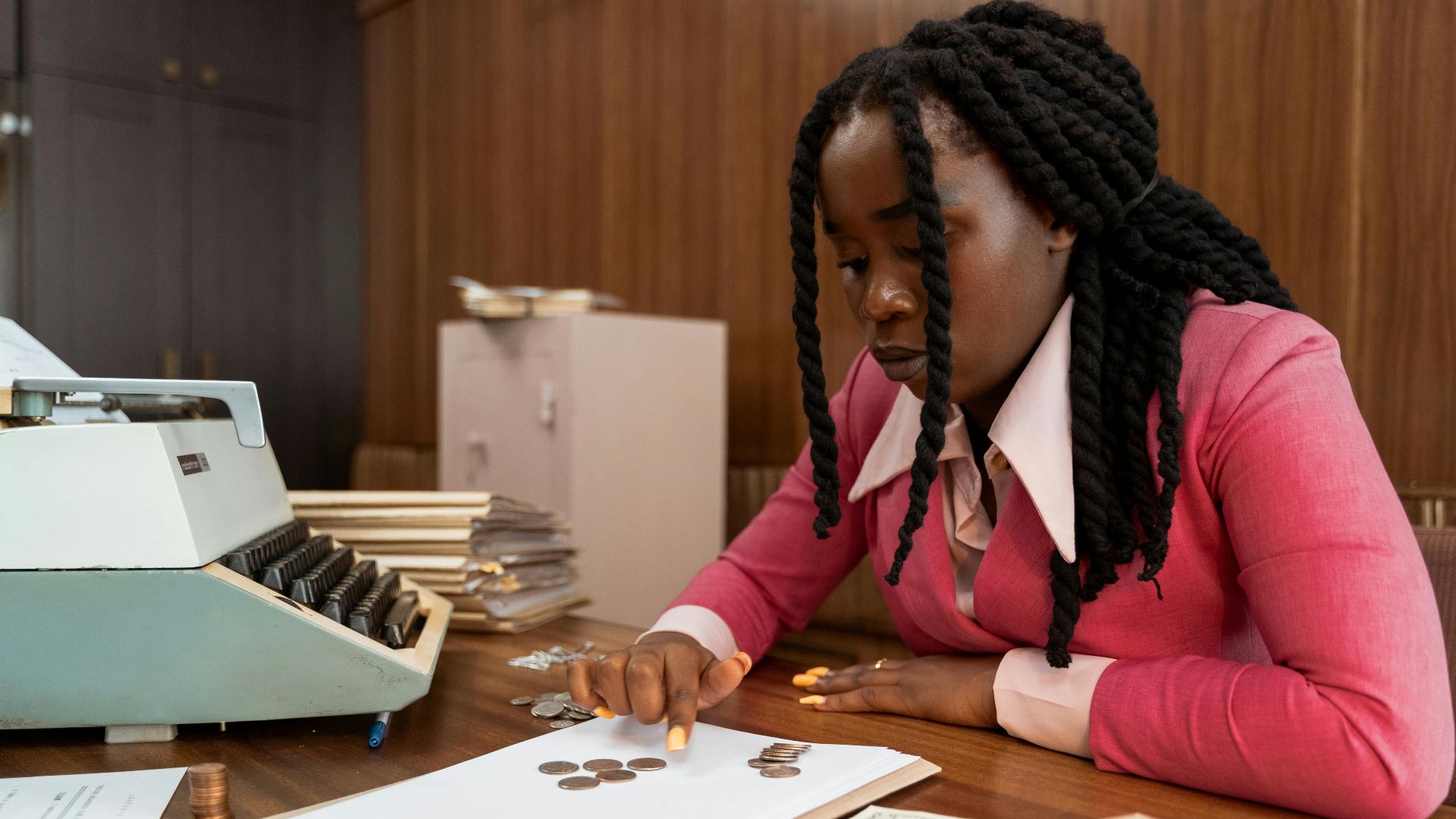 A businesswoman in vintage attire counts coins in a retro office setting.
