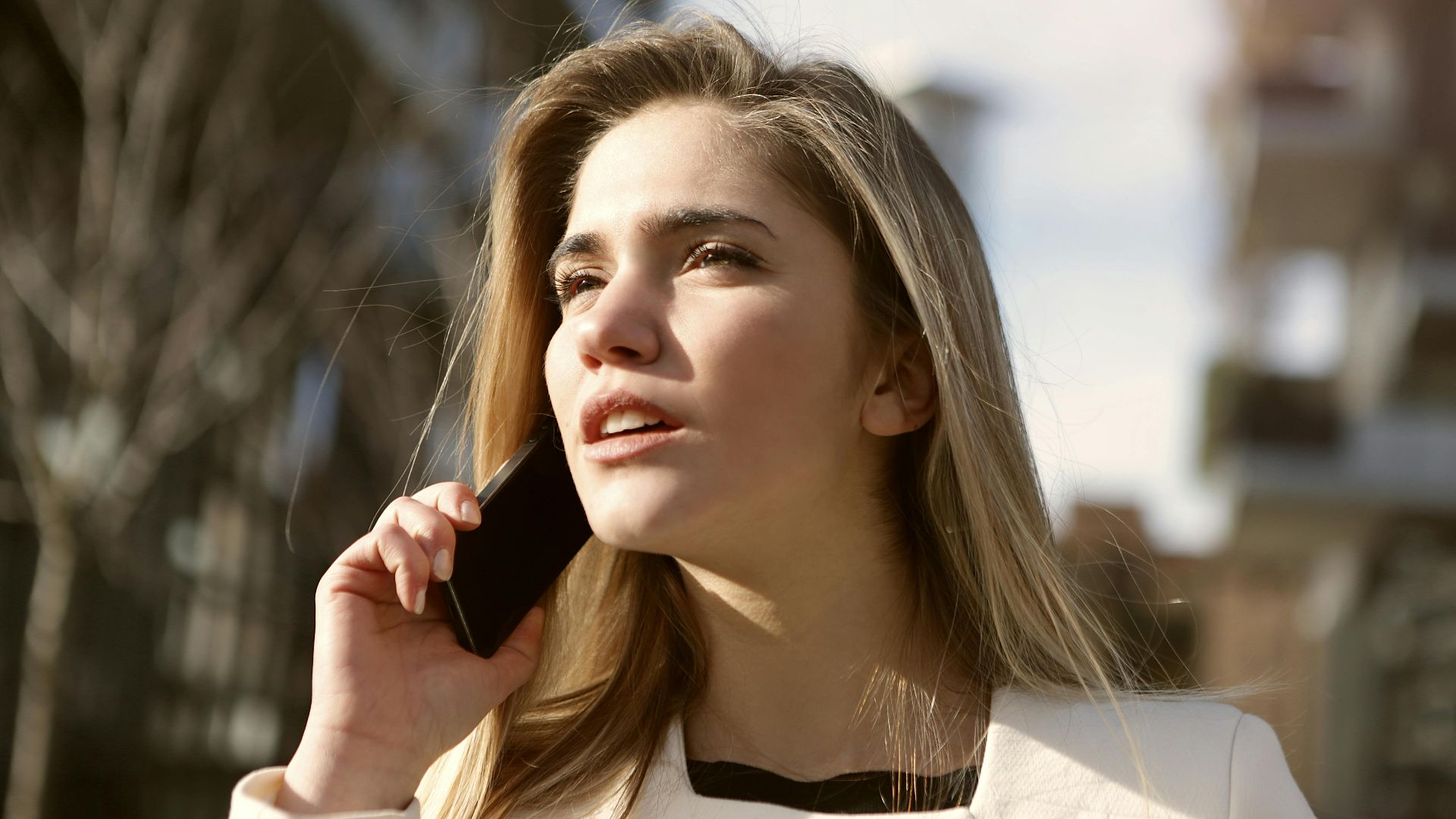 Young woman engaging in a phone call outdoors, capturing a moment of modern communication.