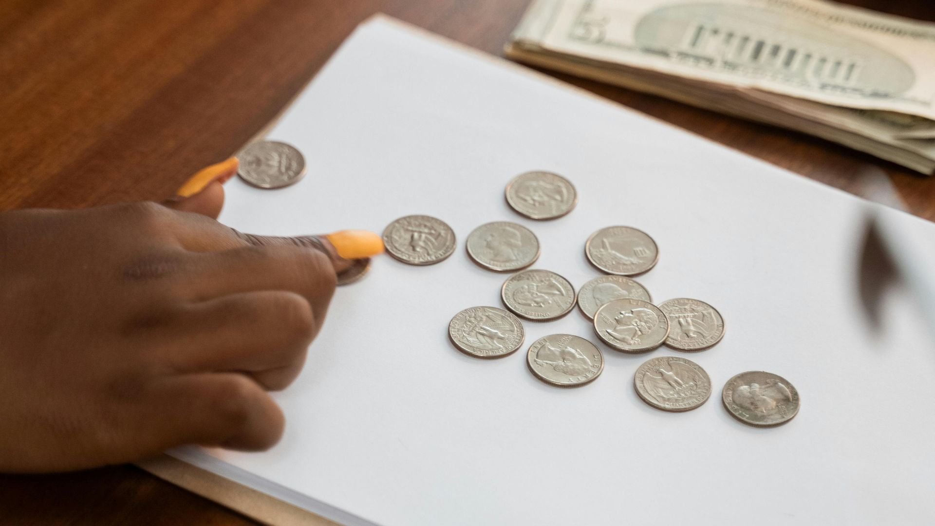 Close-up of diverse hands counting coins on a wooden table, highlighting teamwork and finance.