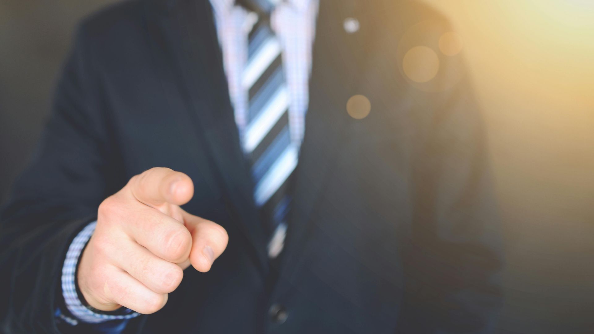 Confident businessman in a suit pointing forward, signifying leadership and focus.