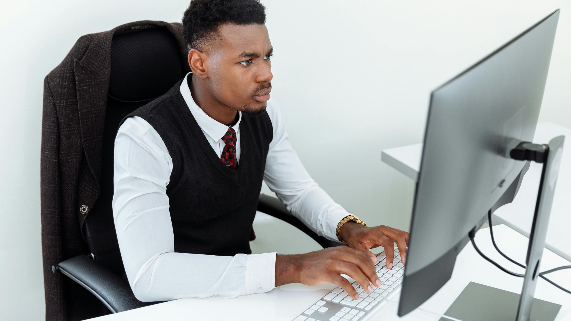Professional man intensely working on a computer at his office desk, focused and determined in a business environment.