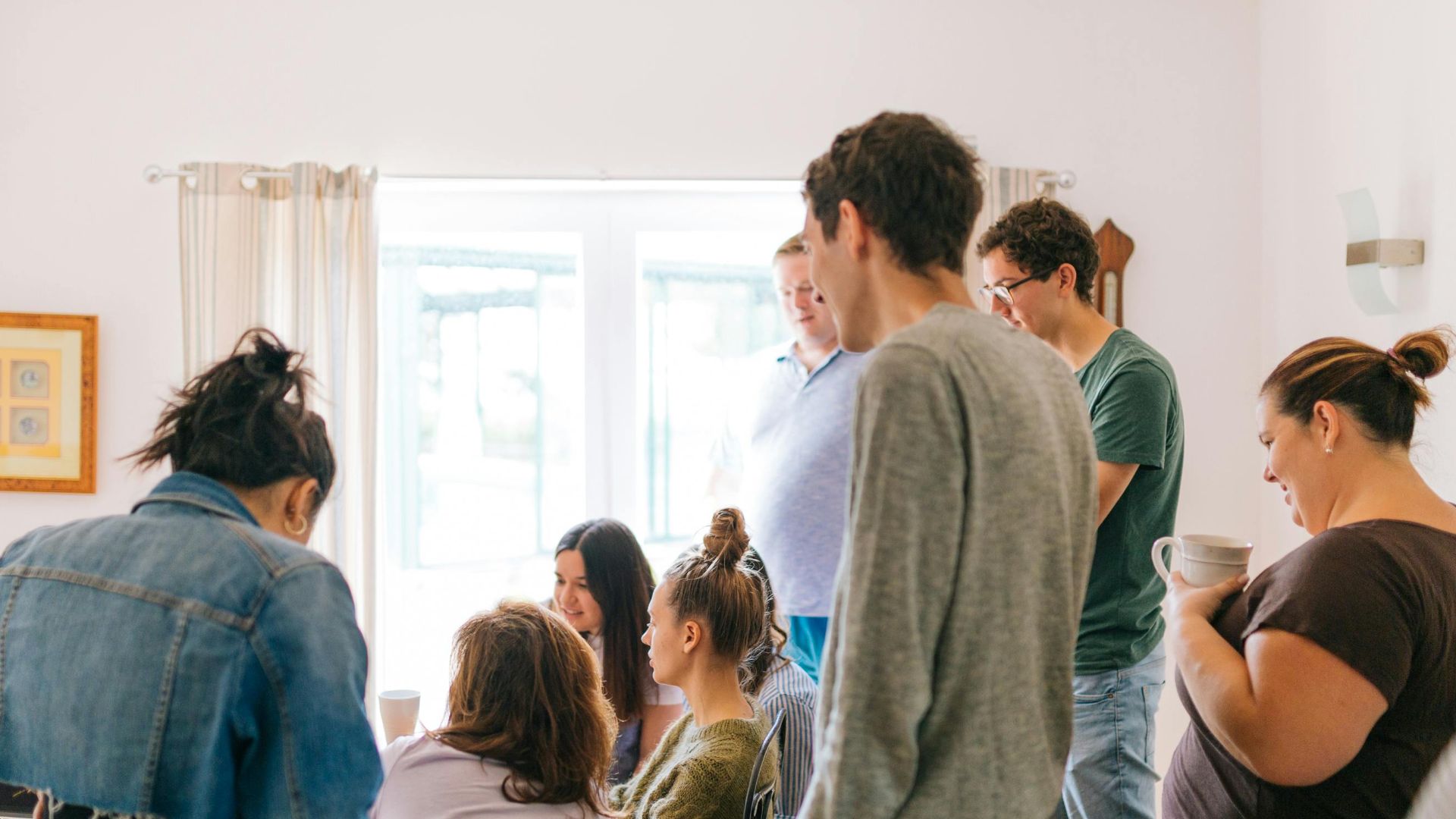 A group of adults collaborating around a table in a bright room, promoting teamwork and creativity.