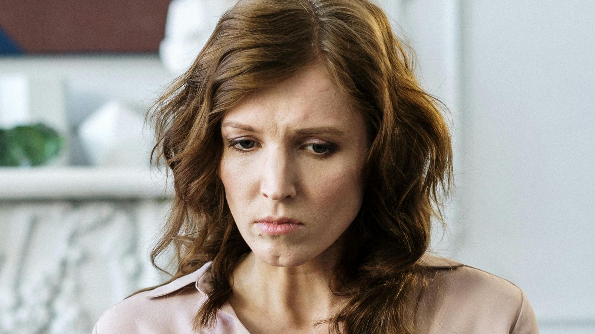 A woman sits pensively on the sofa during a therapy session indoors.