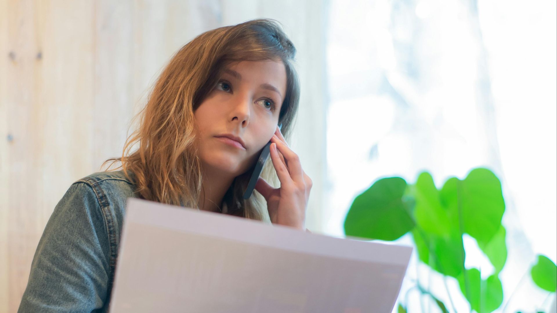 Focused businesswoman reviewing documents in a bright office with natural light.