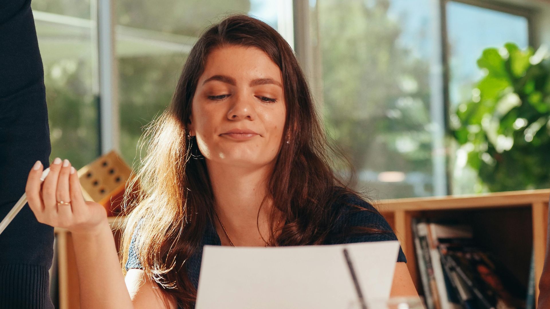 Confident businesswoman analyzing documents in a modern office setting with colleagues.