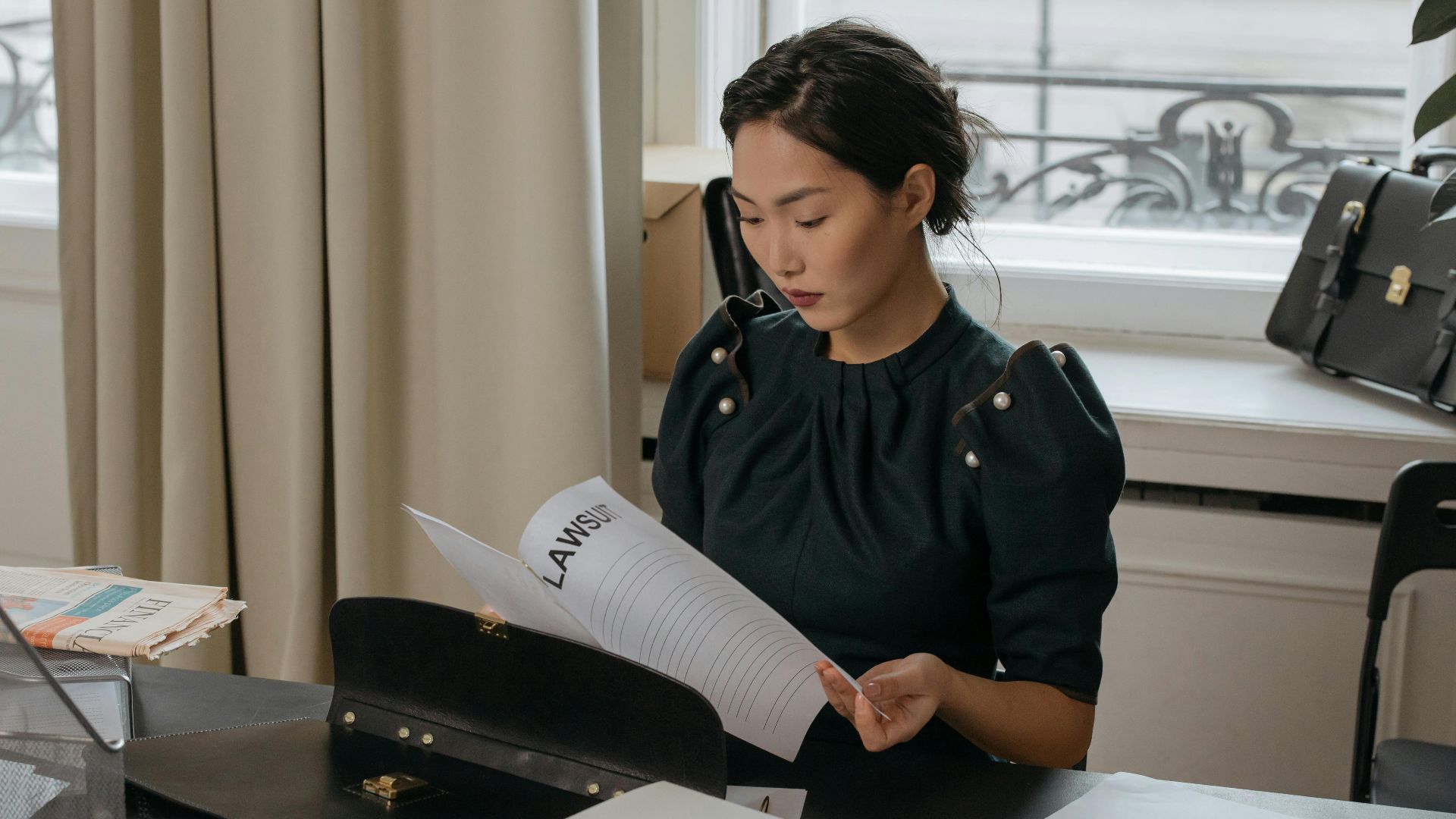 Elegant young woman reading documents in a stylish office setting.