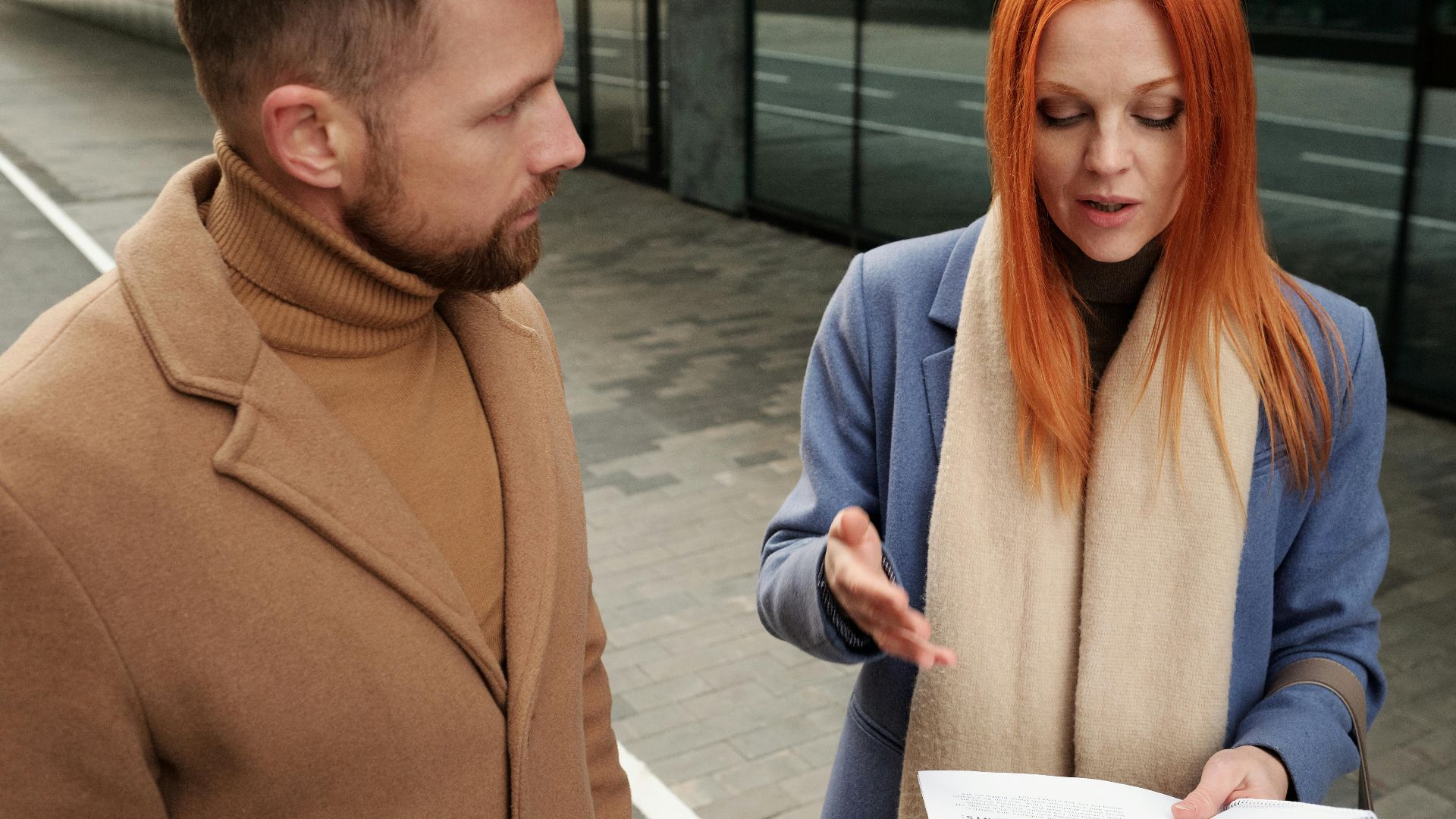 Two professionals engaged in a serious discussion, reviewing documents outdoors.