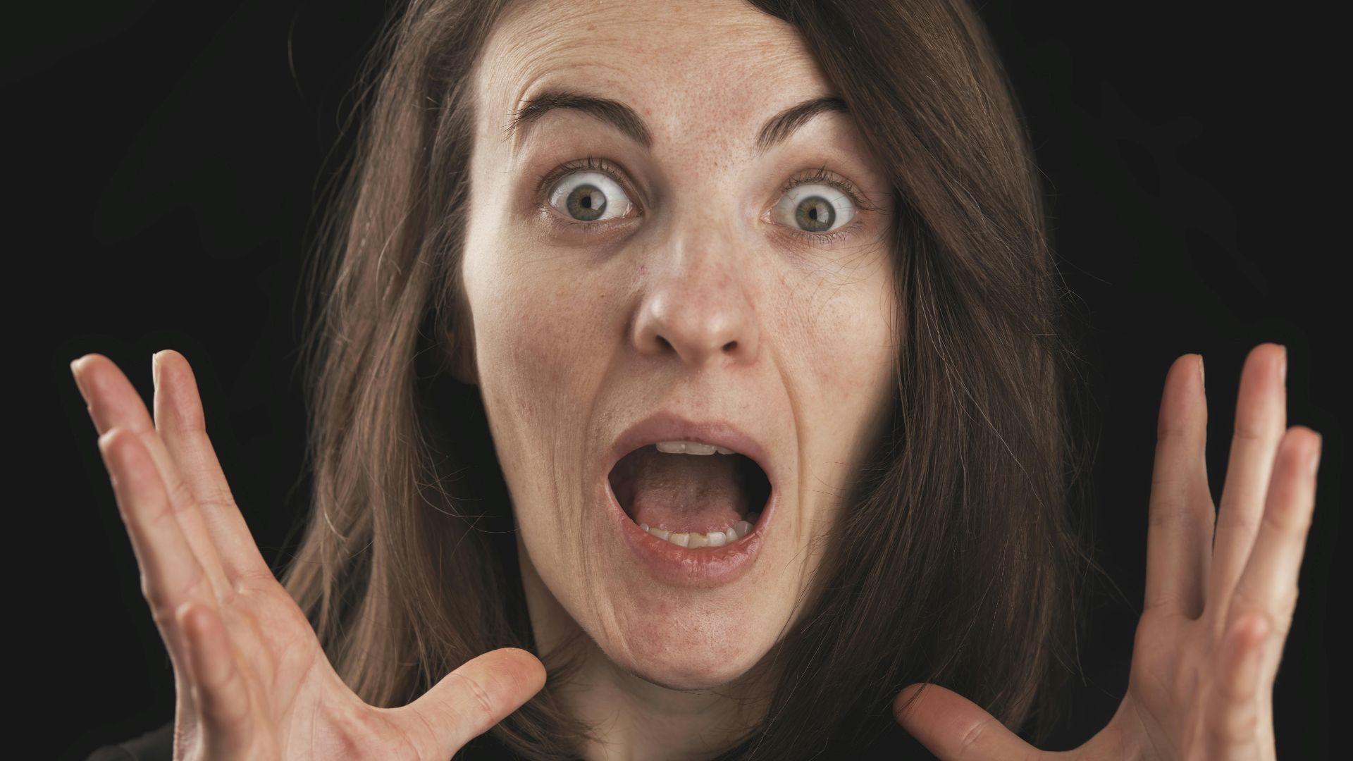 Close-up of a woman expressing shock and surprise with wide eyes and open mouth.