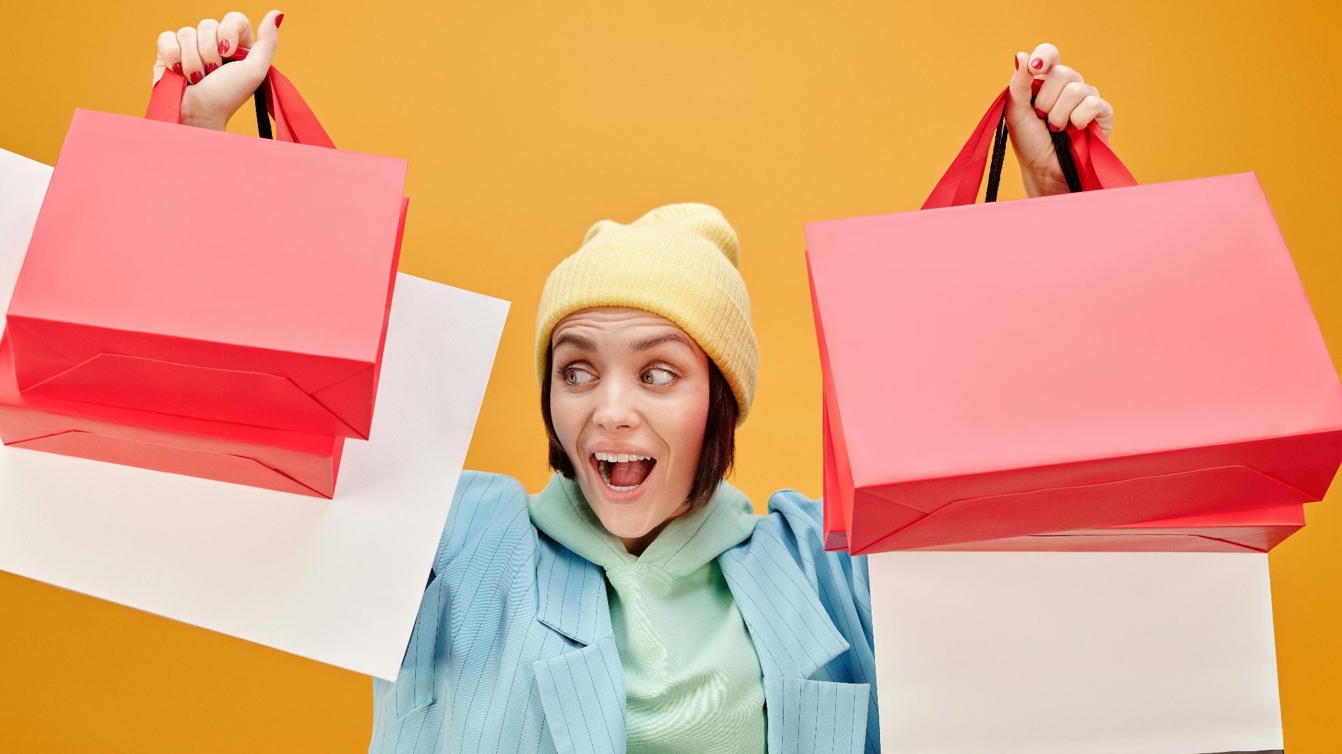 Excited woman holding colorful shopping bags, enjoying a shopping spree.
