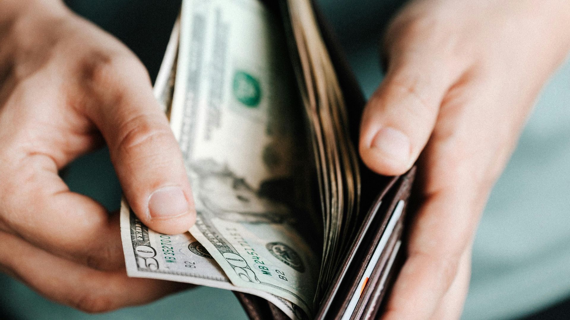 Close-up of hands holding a wallet with cash, depicting financial management.