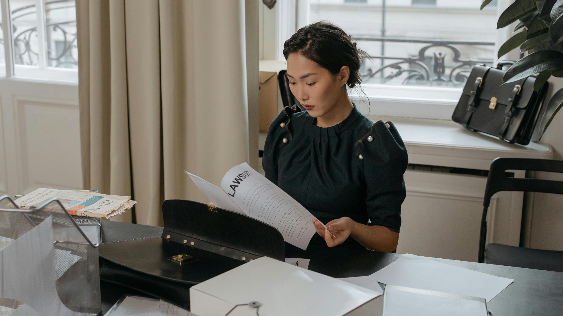 Elegant young woman reading documents in a stylish office setting.