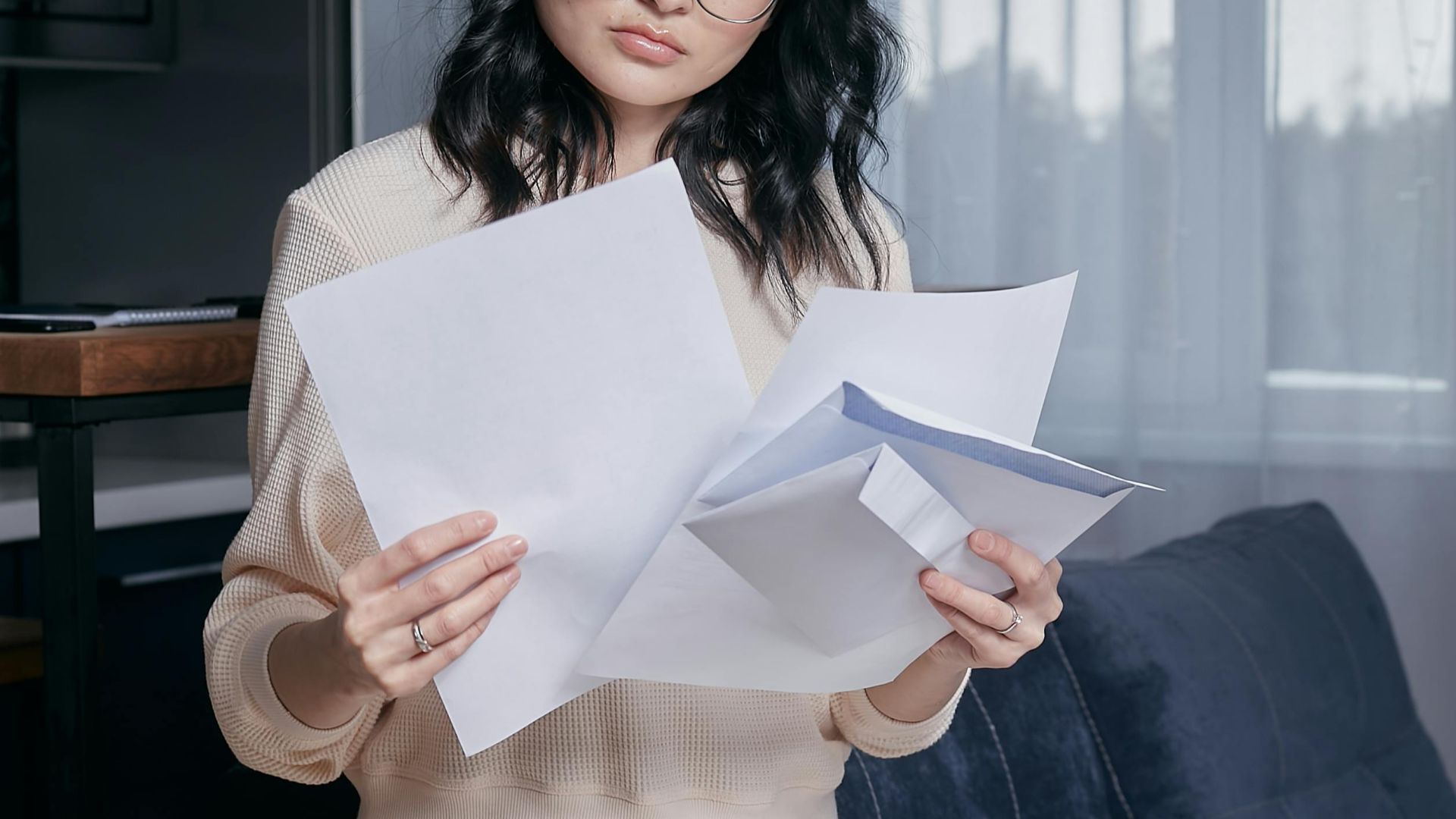 A woman seated indoors carefully reviewing documents, initiating thoughtful analysis.