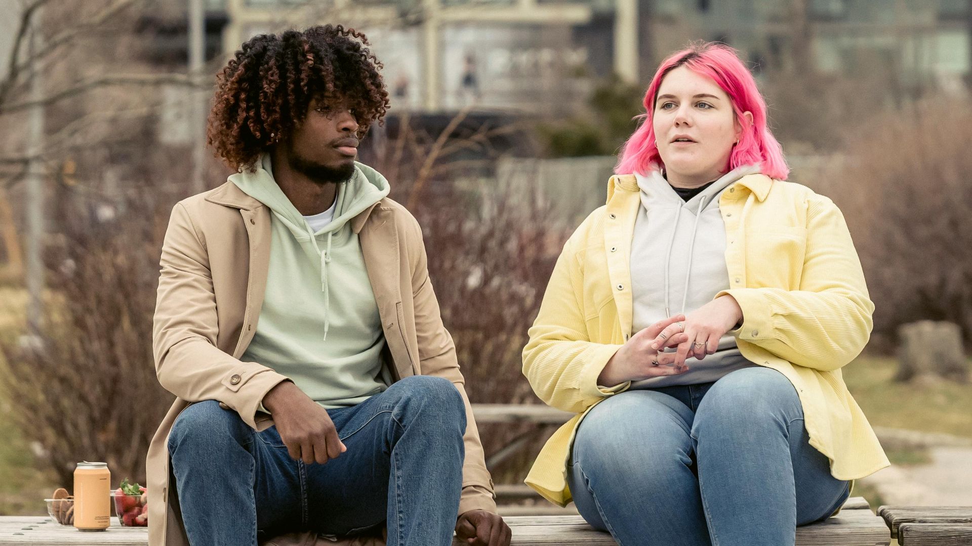 Two diverse friends having a conversation at a picnic table in a city park on a cool day.