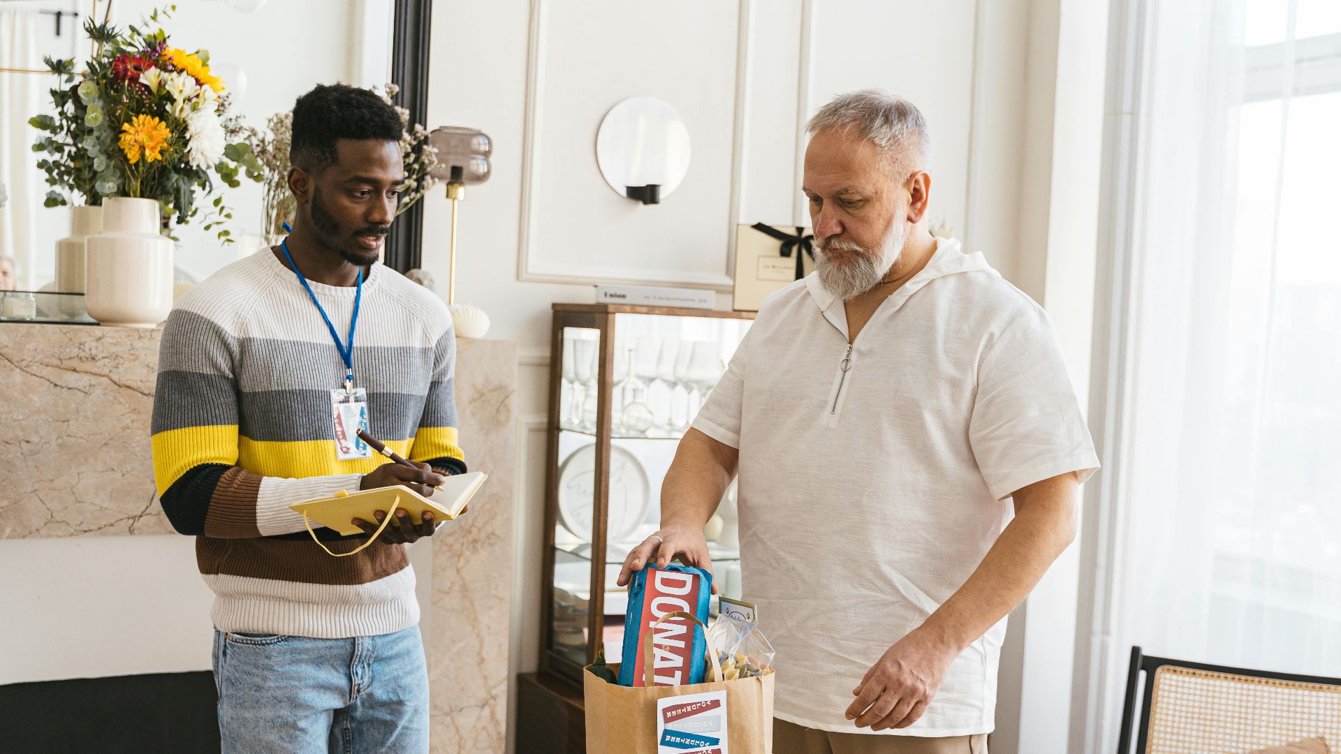 Two male volunteers packing donation bags with essentials indoors.