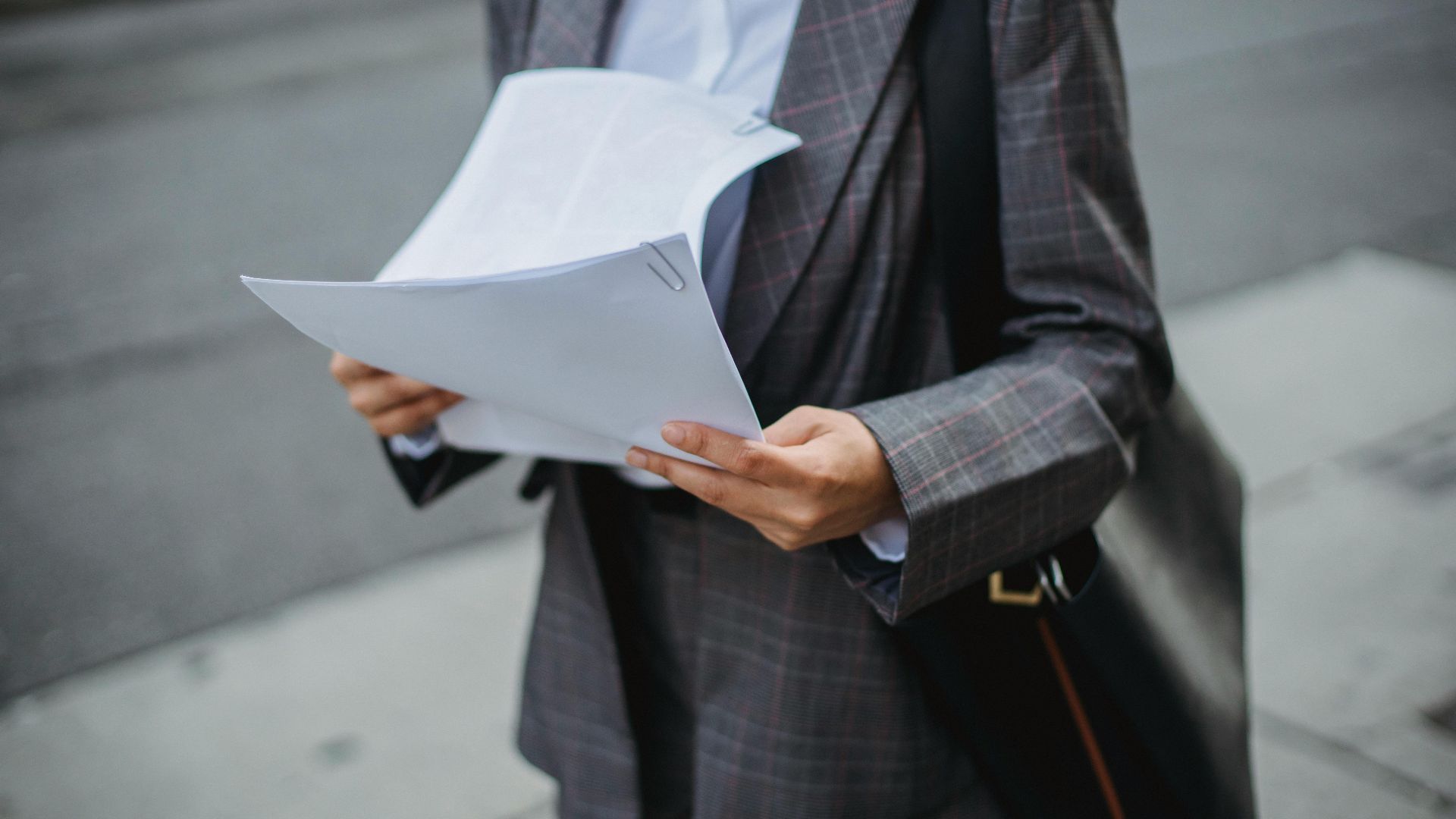 Professional businesswoman reviewing documents outdoors in a city environment.