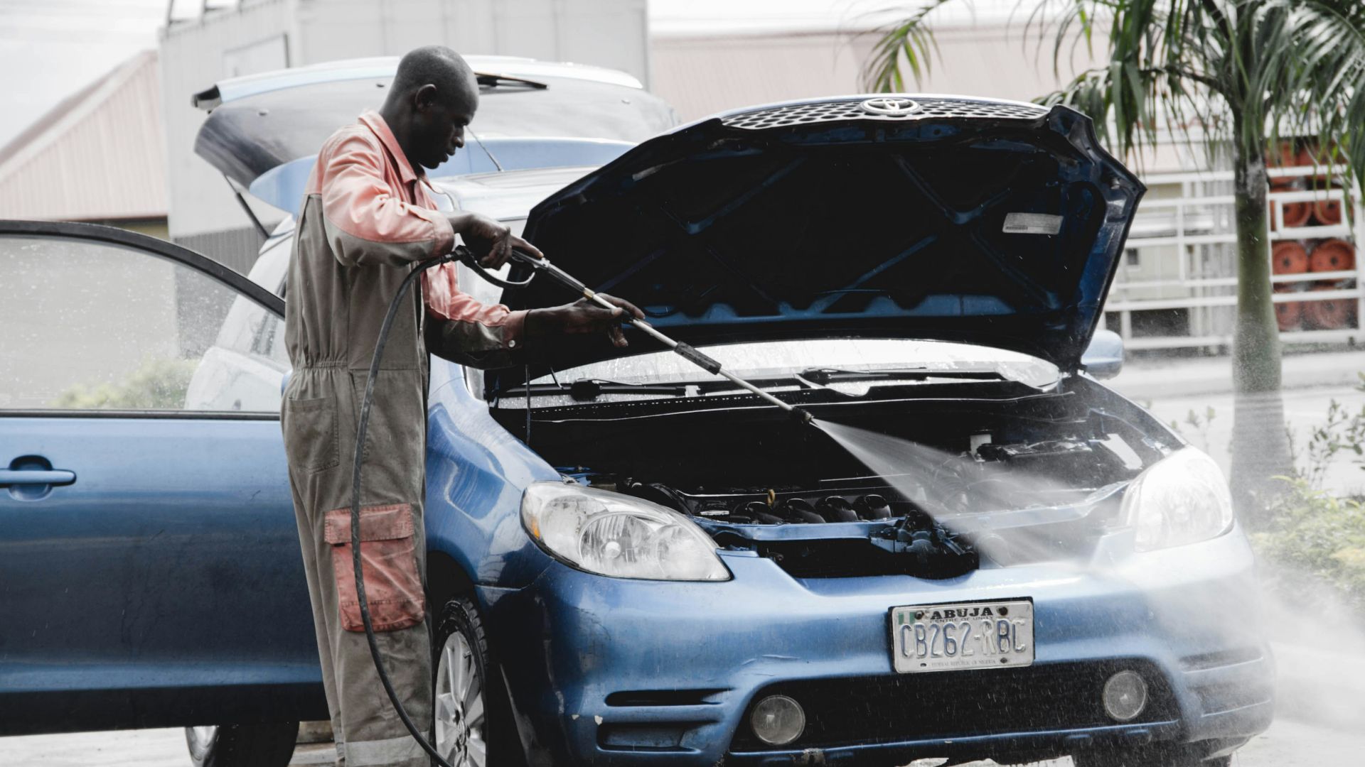 man in gray coat standing beside blue car during daytime