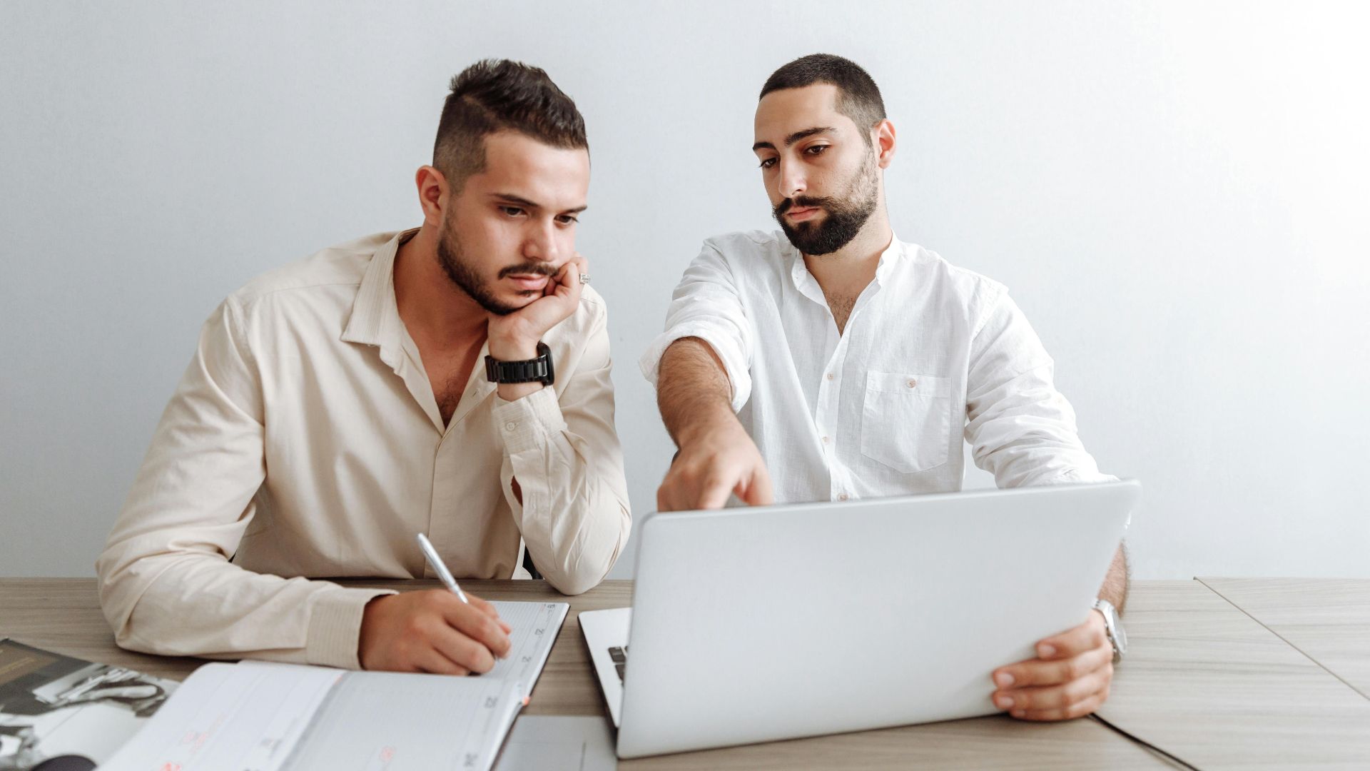 Two businessmen working together on a laptop in an office setting, focusing on a project.
