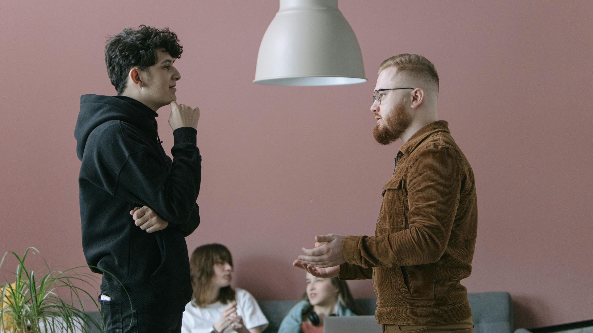 A group of young professionals engaging in a casual office meeting with a modern and stylish backdrop.