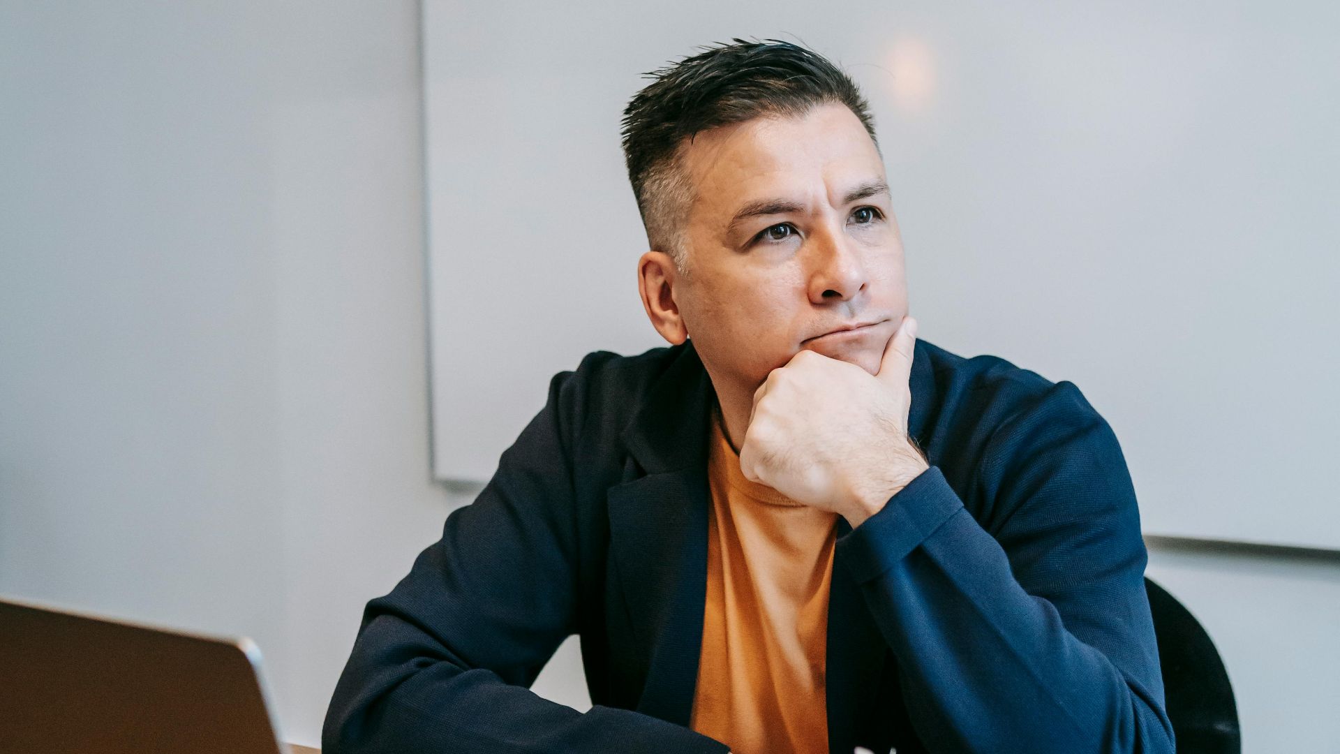 A man sits thoughtfully at a home office desk, embodying remote work contemplation.