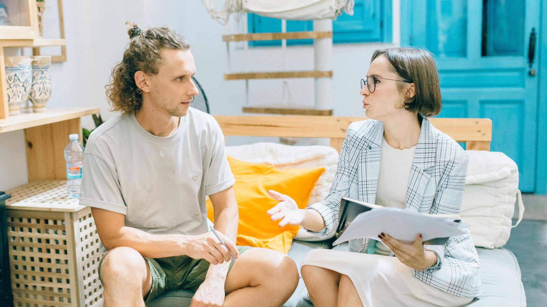 A man and woman discussing work in a stylish, bright living room setting.