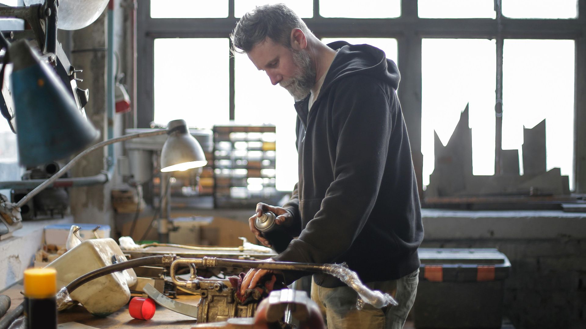 An experienced mechanic concentrates on repairing equipment in a busy workshop.
