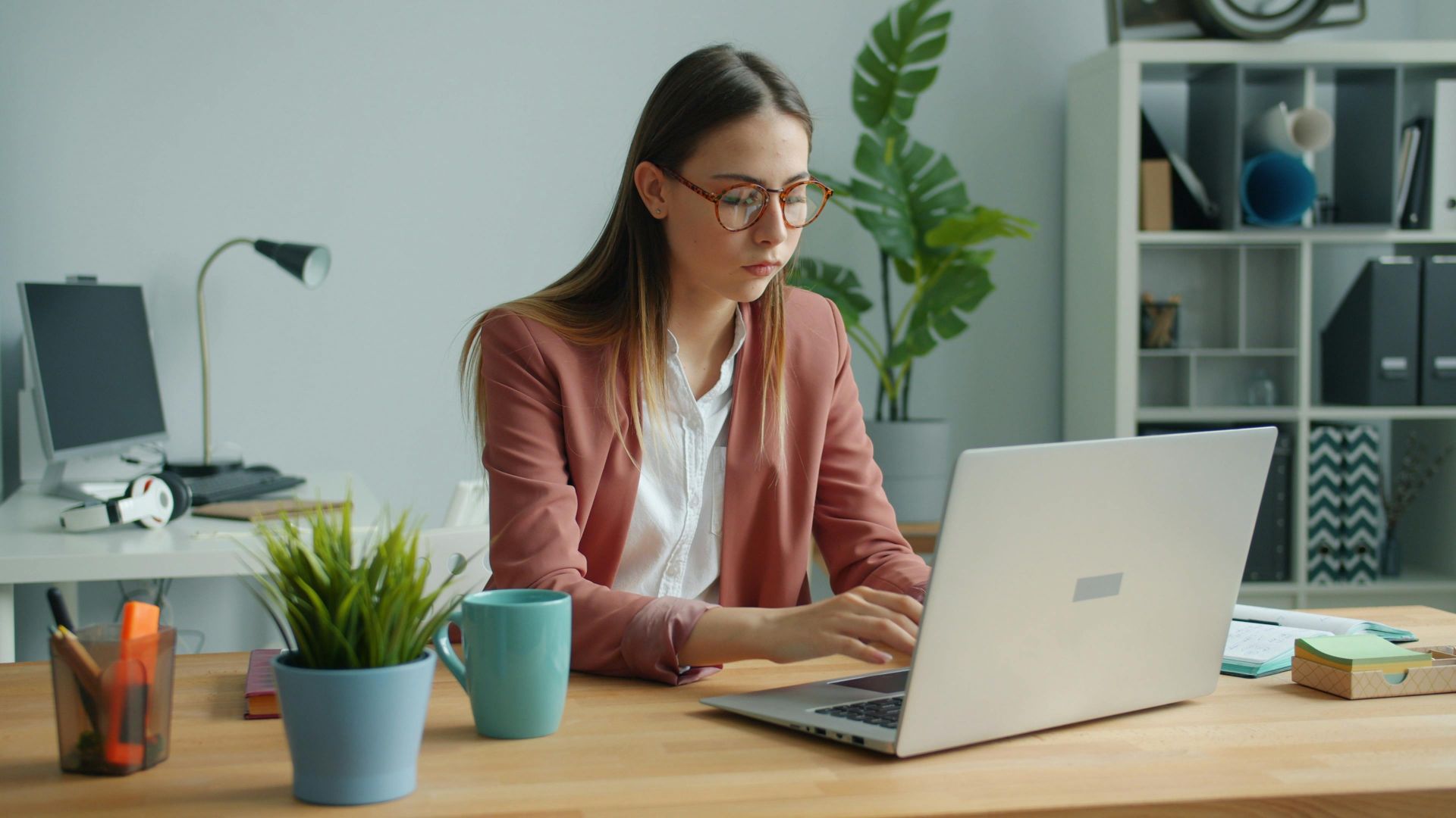 Focused professional woman using a laptop in a modern office setting.