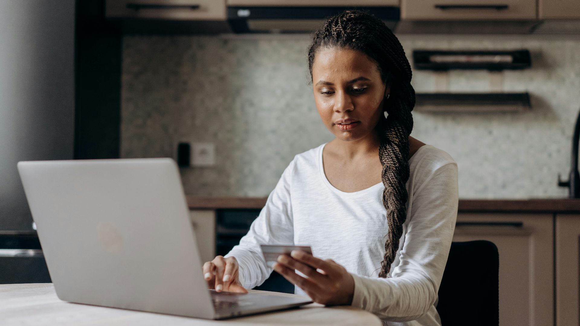 African American woman using laptop and credit card for online shopping at home.
